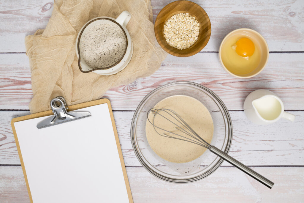 Paper Clipboard With Flour Egg Yolk Milk Oat Bran Wooden Table 1024x683