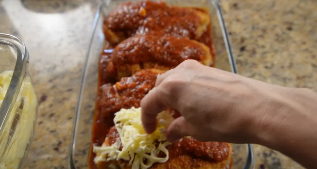 cobrindo filés de frango empanados com queijo mussarela para parmegiana