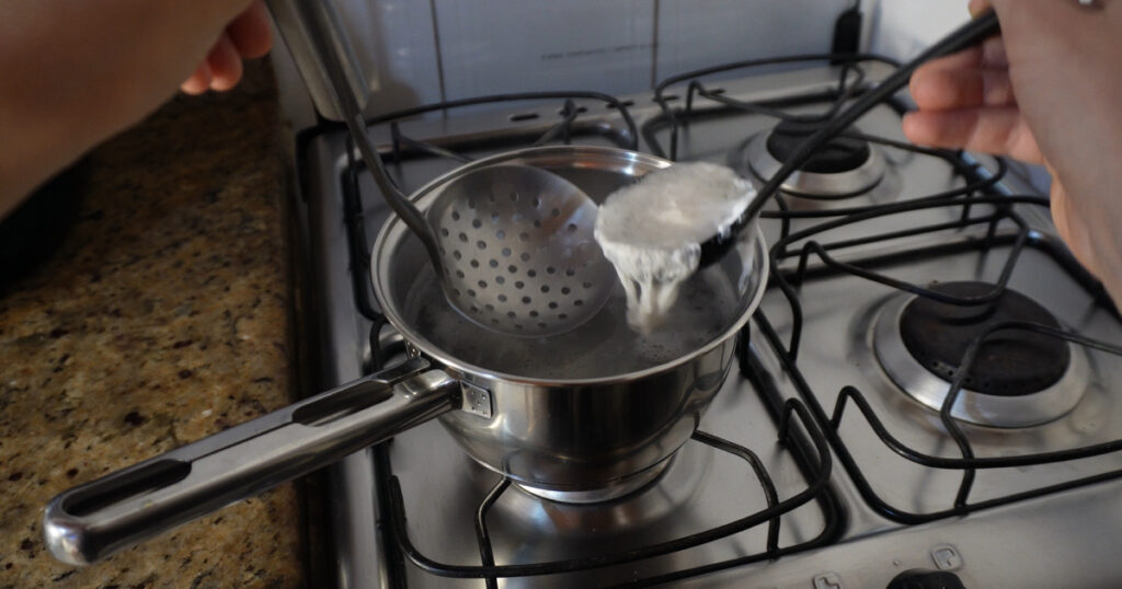 testando receitas ovo pochê com concha sendo retirado da água