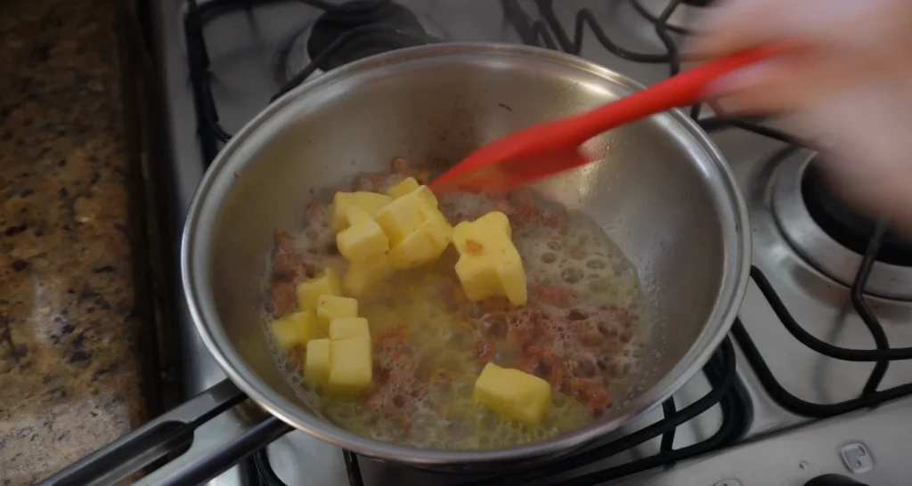 bacon dourando e manteiga derretendo em uma frigideira de inox