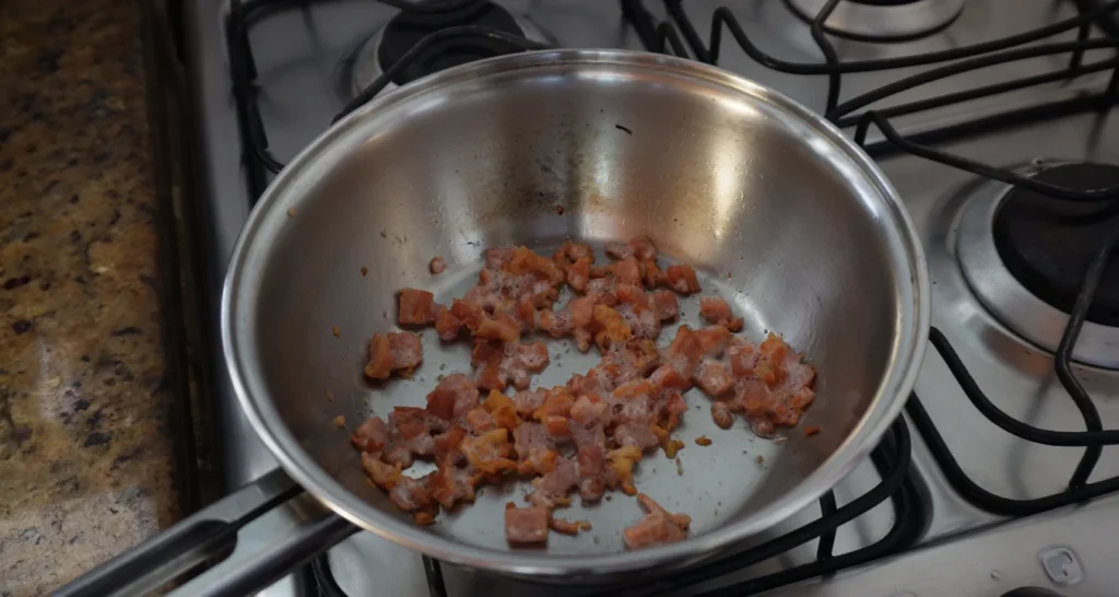 bacon dourando em uma frigideira de inox